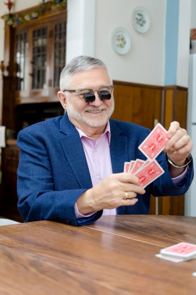 A man wearing low vision glasses playing cards